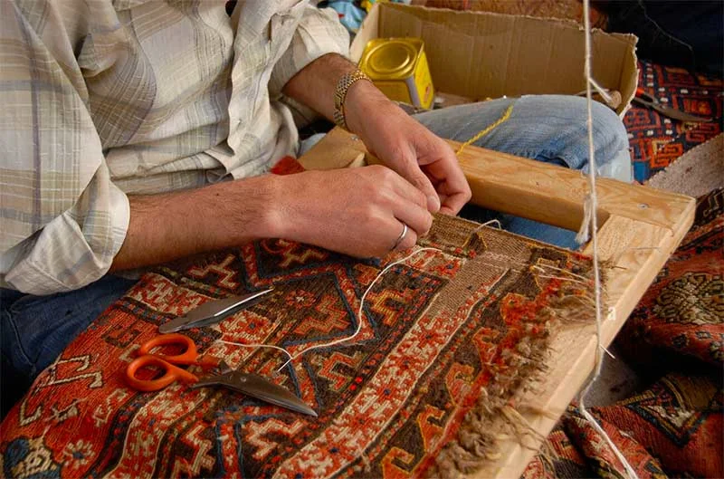 Travail manuel de restauration sur un tapis à motifs